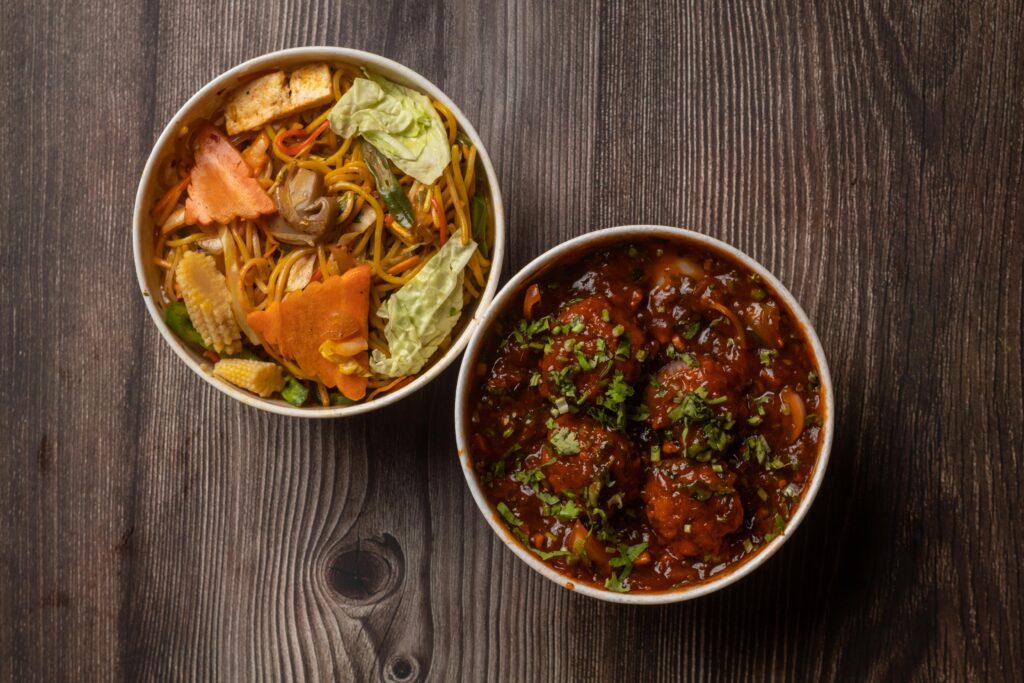 Different kinds of manchurian in two bowls on a brown wooden table